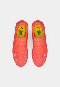 Lyse neonpink atletik-sko med en tekstureret overdel, reflekterende detaljer og gule indlægssåler med en QR-kode og branding.