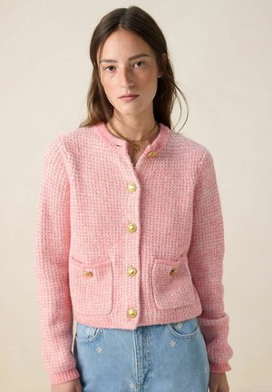 Roze gebreide cardigan met een gestructureerde afwerking, voorzien van gouden knopen en twee voorzakken. Lange mouwen en een ronde halslijn maken het ontwerp compleet.