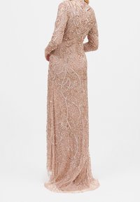 Blandet, gulvlængde kjole i blød lyserød med lange ærmer, der har indviklede svunget mønstre og en gennemsigtig bund, der fremviser fine udsmykninger.