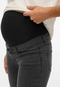 Rasedate teksad musta veniva vöökohaga, halli denimi kangast, istuva lõikega ja peente õmbluse detailidega taskute ümber.