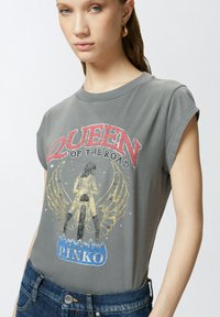 T-shirt grigio a maniche corte con stampa grafica di una figura con ali, testo "REGINA DELLA STRADA" e il nome del marchio "PINKO" in basso.