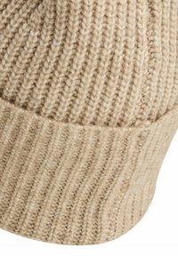 Beige knit hat featuring a ribbed texture, rounded crown, and a folded cuff for added warmth and style.