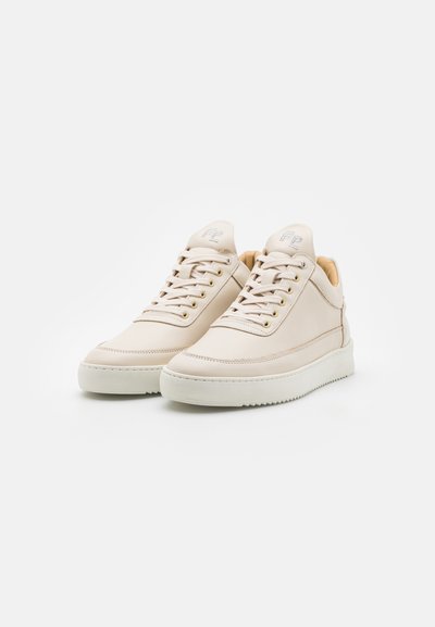 Bézs bőr sneaker, sima felülettel, kerek orral és fehér gumitalppal. Párnázott nyelvvel és aranyszínű fűzőlyukakkal rendelkezik.