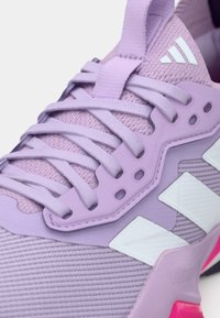 Baskets de sport violettes avec un dessus en mesh respirant, un système de laçage ajustable, des accents blancs et une semelle rose.