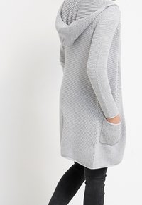 Světlě šedý pletený kardigan s kapucí, texturovaným vzorem, předními kapsami, dlouhými rukávy a volným střihem, vhodný pro každodenní nošení.