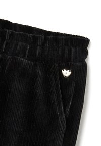 Zwarte fluwelen broek met een gestructureerd ribbelontwerp, voorzien van een elastische tailleband en een klein zilveren hartvormig accent.