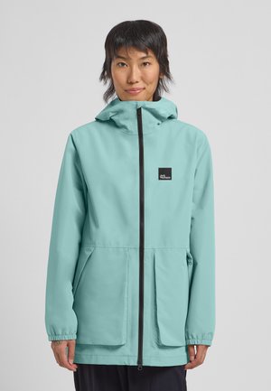 Veste imperméable bleu clair avec capuche, fermeture éclair avant et deux poches inclinées. Dotée de poignets élastiques et d'un petit logo noir sur la poitrine.