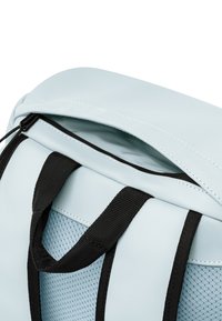 Hellblaue Rucksack mit schwarzem Mesh-Seitenbereich, oberen Reißverschlussverschluss, gepolsterten Trägern und kontrastierenden Nähdetails.