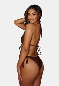 Brun bikini med halterneck och knytbikiniunderdelar. Tyget verkar mjukt med minimal täckning och justerbara knyt för passform.