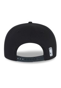 Gorra de béisbol de tela negra con visera plana, correa de plástico ajustable en la parte trasera y un parche del logo de la NBA en blanco. Textura lisa.