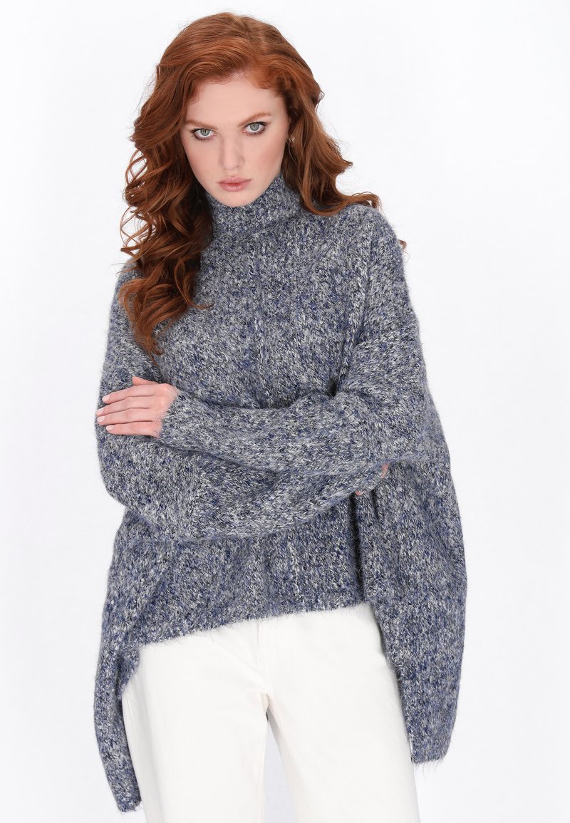 Oversized sweter z golfem w melanżowym niebiesko-szarym dzianinie. Posiada długie rękawy i asymetryczny dół, podkreślając miękką teksturę i przytulny design.