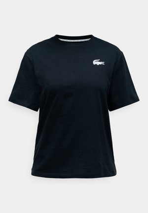 Must musta T-särk lühikeste varrukatega, millel on vasakul rinnal väike valge tikitud krokodilli logo. Klassikaline ümmargune kaelus.