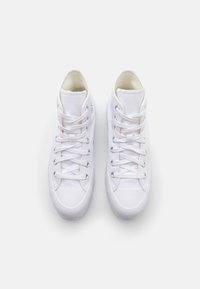 Zapatillas altas de lona blanca con acabado texturizado, que presentan puntera redonda, cordones planos y ojales de metal. Diseño minimalista con marca sutil.