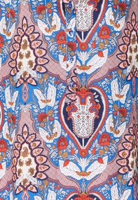 Tessuto blu con motivi floreali in rosso, bianco e giallo. Presenta bottoni e disegni intricati, tra cui cuori e foglie.