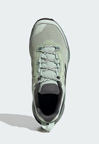 Zapatillas de malla en verde claro con acentos grises, seis ojetes para cordones, cuello acolchado y suela de goma negra para tracción.