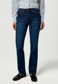 Jeans blu scuro con vestibilità a gamba dritta, realizzati in denim. Presentano un classico design a cinque tasche e delicati accenti di cucitura arancione.
