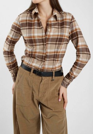 Camicia a scacchi marrone e beige con chiusura a bottoni, decorazioni sulle spalle e colletto. Maniche lunghe e texture del tessuto morbida.