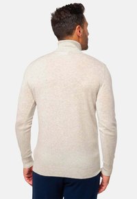 Helle beige Rollkragenpullover aus weichem, strukturiertem Stoff. Verfügt über lange Ärmel und eine taillierte Silhouette, mit gerippten Bündchen und Saum.