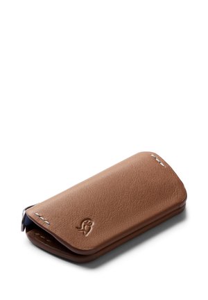 Custodia per telefono cellulare in pelle marrone con una texture liscia, bordi arrotondati e un'impronta del logo; presenta una chiusura a patta e cuciture minime.