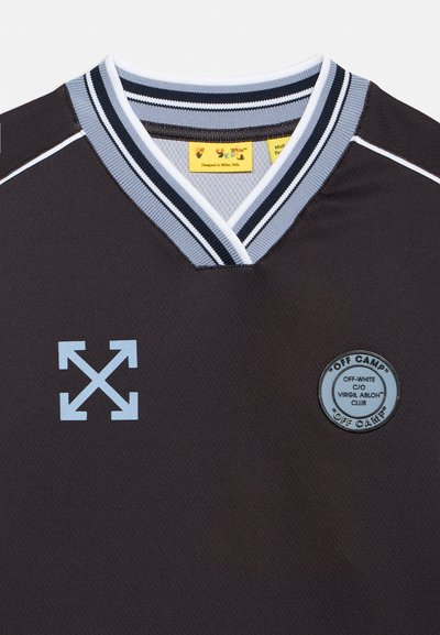 Μαύρη αθλητική φανέλα με ριγέ λαιμόκοψη σε σχήμα V, λογότυπο βελών στο αριστερό στήθος, στρογγυλό έμβλημα με το κείμενο "Off Camp" και το όνομα της μάρκας στο δεξί στήθος.