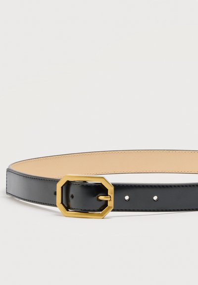 Μαύρη δερμάτινη ζώνη με μπεζ εσωτερική επένδυση και χρυσή οκταγωνική μεταλλική αγκράφα, τοποθετημένη επίπεδα.