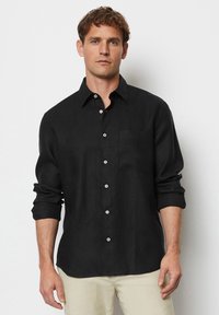 Zwarte linnen button-up shirt met lange mouwen, een borstzak en witte knopen, met een ontspannen pasvorm en een gladde textuur.