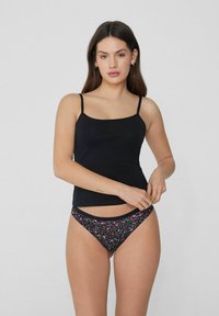Haut sans manches noir et bas de bikini noir à imprimé floral. Le haut a des bretelles fines ; les bas présentent un motif floral coloré et une ceinture contrastante.