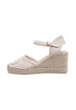 Sandalia de cuña en tejido beige claro, con detalles bordados, una correa de tobillo texturizada y una plataforma de yute trenzado.