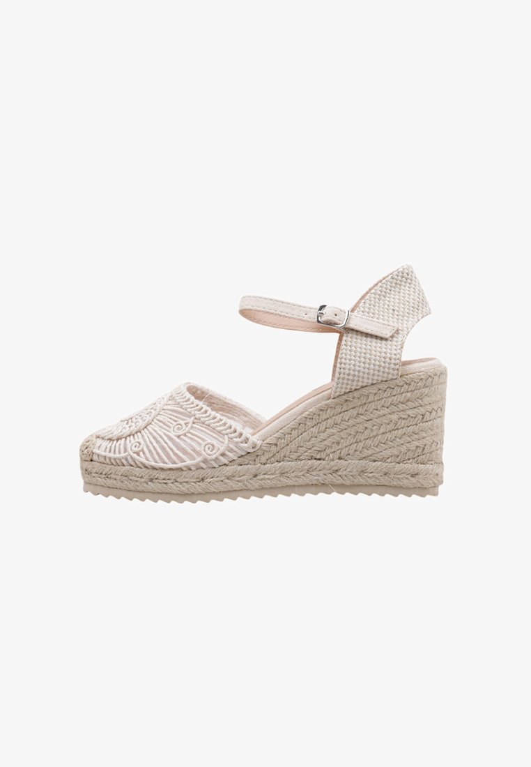Sandale compensée en tissu beige clair, avec des détails brodés, une bride de cheville texturée et une plateforme en jute tissée.