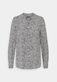 Blusa a maniche lunghe in bianco e nero con scollatura a V e dettagli con bottoni; presenta un motivo a pois sparsi su un tessuto leggero.