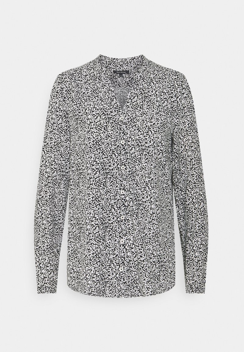 Long-sleeve blouse in black and white with a v-neck and button detail; features a scattered dot pattern on a lightweight fabric.