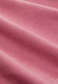 Różowa bawełniana tkanina o gładkiej fakturze, z delikatnym ukośnym prążkowaniem. Zmarszczenia tworzą różne odcienie różu na powierzchni.