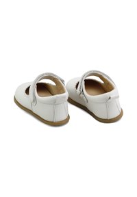 Zapatos Mary Jane de cuero blanco con recortes y una correa. Textura suave, forma redonda y suela de goma marrón clara.