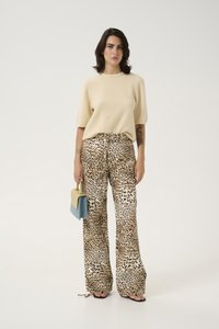 Beige short-sleeve knit sweater, animal-print wide-leg trousers, holding a two-tone handbag in yellow and blue, flat sandals.