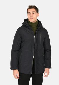 Giacca nera imbottita con cappuccio, dotata di chiusura con zip frontale, tasche laterali e una piccola tasca sul petto. Il tessuto ha una texture liscia.