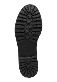 Suela de zapato de goma negra con profundas estrías, con patrones de estrellas y agujeros de drenaje. Marcada con las etiquetas "GEOX" y "PATENTE ITALIANA".