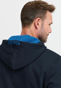 Felpa navy con cappuccio interno blu e scritta sul retro "FQ1924" in blu. Tessuto morbido, design classico e cappuccio regolabile con cordino.