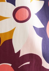 Tessuto floreale con grandi fiori bianchi e rosa, impreziosito da dettagli viola scuro, su uno sfondo chiaro con tocchi di giallo caldo.