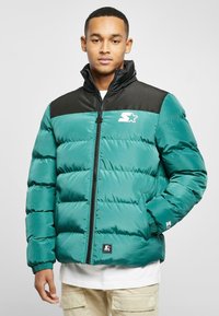 Teal puffer jacket with black accents, zip closure, and stand collar. Features quilted texture and logo on the chest and sleeve.