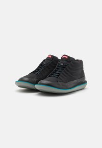 Black mid-top shoes made of textured material, featuring a sleek design, turquoise accents on the sole, and contrasting red logo on the tongue.