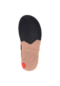 Suela de zapato marrón con un patrón en zigzag, que presenta la marca "Kickers" y el número "70" sobre un fondo color durazno, acentuado por un botón rojo en el talón.