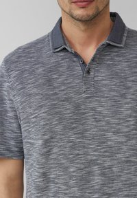 Szaro-granatowa koszulka polo w paski, wykonana z teksturowanej tkaniny, z dwiema guzikami i kontrastowym wykończeniem kołnierzyka.