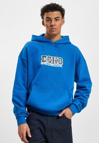Modrá mikina s kapucňou a klokankou, s nápisom "ECKO unlimited" v bielej a šedej farbe. Mäkká tkanina s pohodlným strihom a sťahovacou kapucňou.