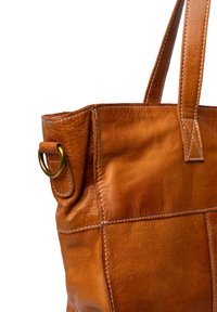 Sac en cuir brun avec une texture lisse, deux poignées et un accent en anneau en laiton. Les coutures blanches contrastent avec la couleur du cuir.