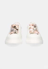 Zapatillas blancas con una superficie lisa, adornadas con cintas de satén en tonos rosa empolvado y plata, decoradas con joyas y perlas.