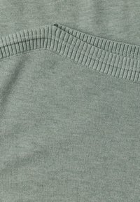 Gros plan d'un tissu tricoté gris clair avec des bords côtelés formant un motif doux et texturé.