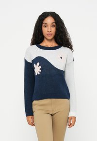 Strickpullover mit einem Wellenmuster in Marineblau und Hellgrau, verziert mit floralen Akzenten in Pink und Weiß. Rippbündchen und Saum, weicher Stoff.