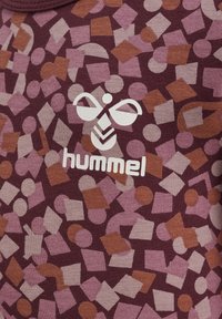 Bordeaux gemusterde stof met onregelmatige vormen in lichtroze en oranje. In het midden is het witte logo van het merk "hummel" zichtbaar.