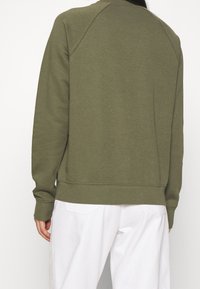 Olivgrön sweatshirt med rund hals, långa ärmar och ribbade muddar. Mjuk tygkvalitet, avslappnad passform, enkel design utan synliga logotyper.