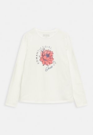 Camiseta blanca de manga larga con un gran gráfico de una flor rosa, texto "Romantic Girl" arriba y el logo "Guess" debajo de la flor en el centro frontal.
